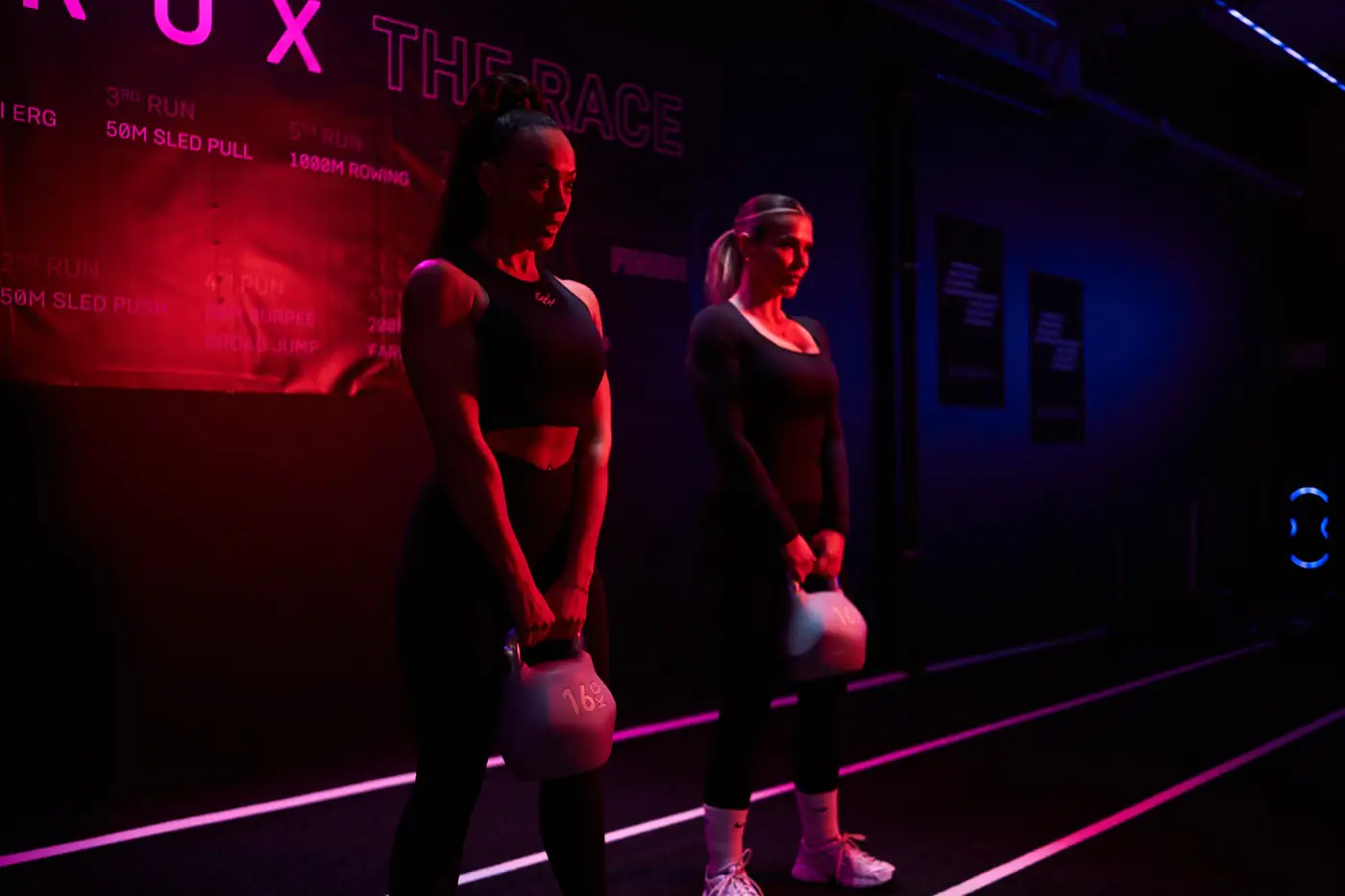 Athletin trägt zwei Kettlebells beim Farmers Carry