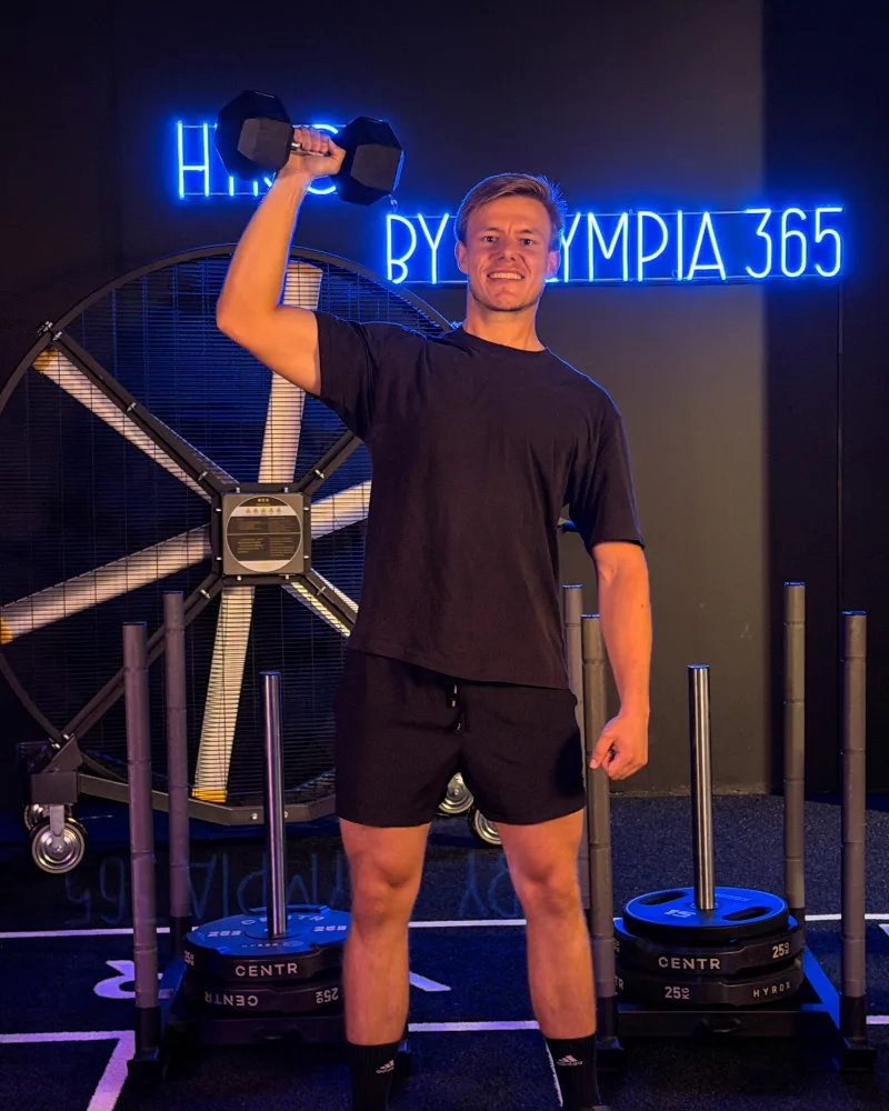 Marvin mit Kurzhantel vor dem HYROX Neonschild bei OSF 365