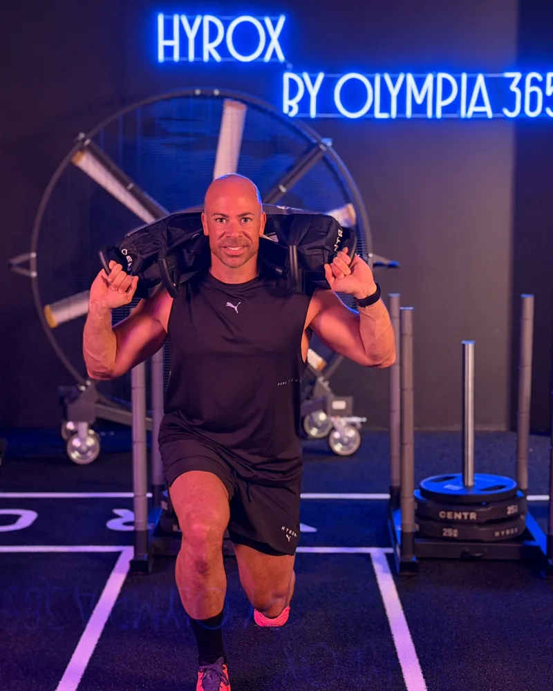 Pietro mit Sandbag vor dem HYROX Neonschild bei OSF 365