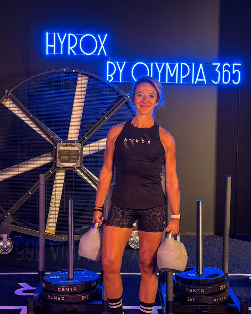 Tina mit Kettlebells vor dem HYROX Neonschild bei OSF 365